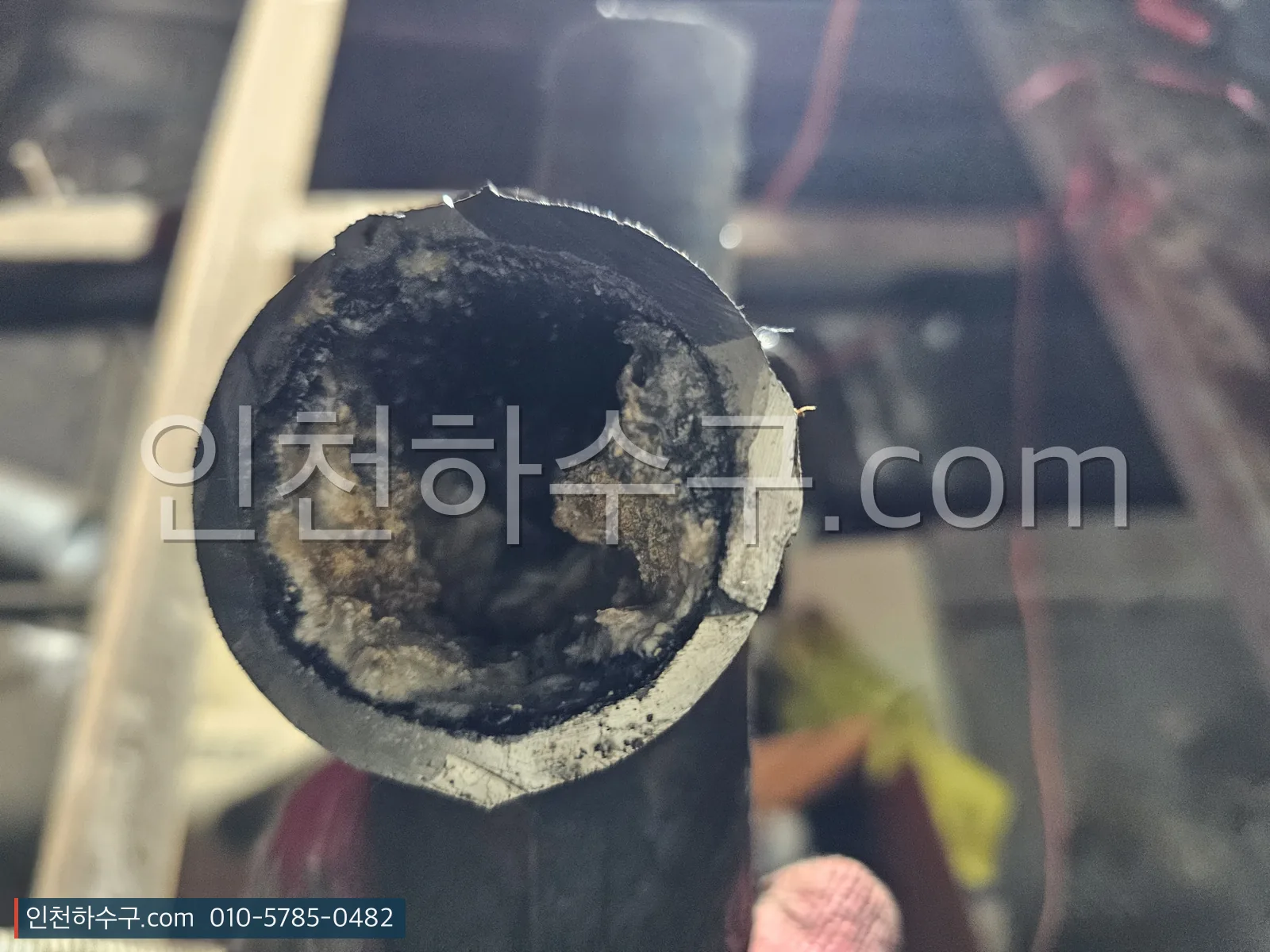 잘라낸 배관 단면 — 스케일이 두껍게 앉아 관 내부가 좁아진 상태