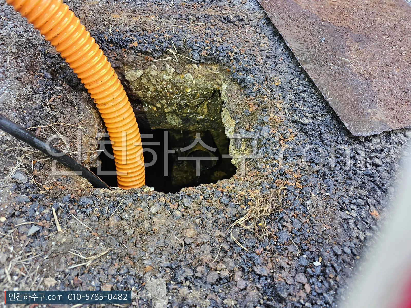 옥외 맨홀에 고압세척 호스를 투입해 준설하는 장면