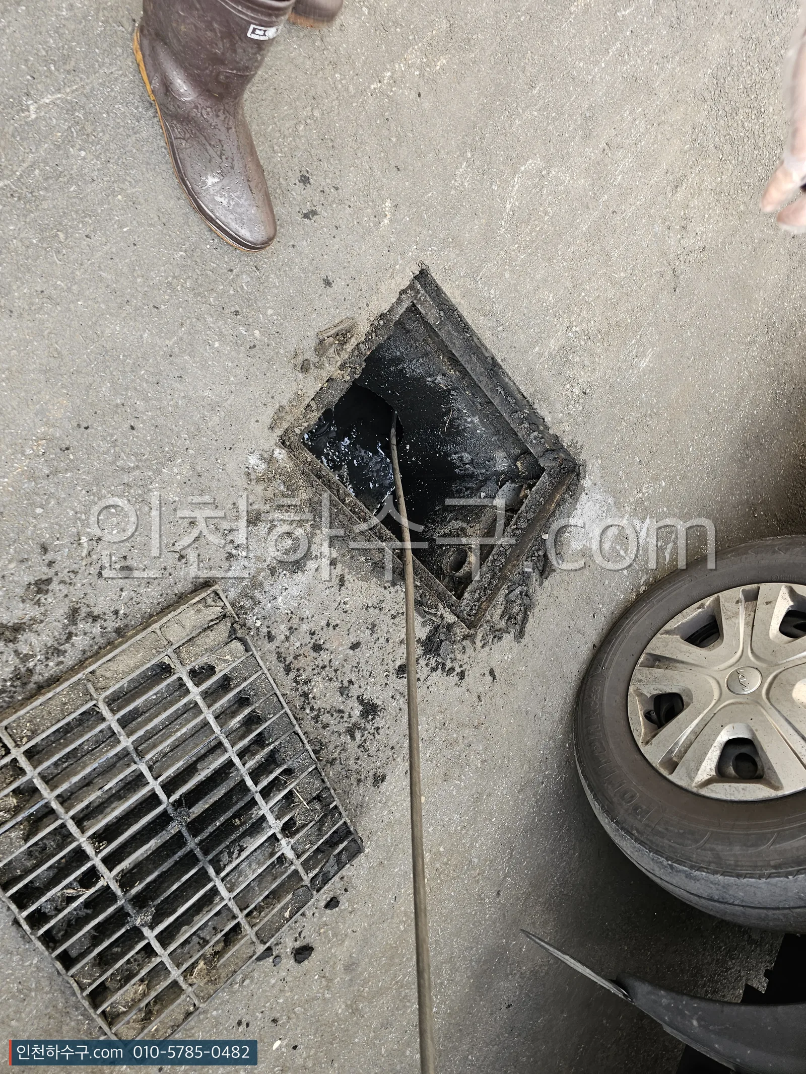 주차장 트렌치 그레이팅을 들어내고 퇴적물을 걷어내는 장면